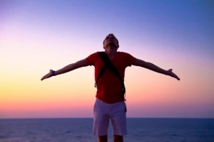 hombre encima de una montaña al atardecer con los brazos abiertos